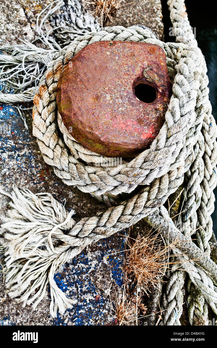 Fishing boat rope tied to a mooring bollard, in the harbour. Stock Photo