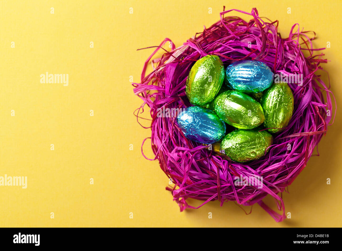 Easter eggs in pink nest. Holiday composition on yellow paper background. Top view. Macro shot Stock Photo