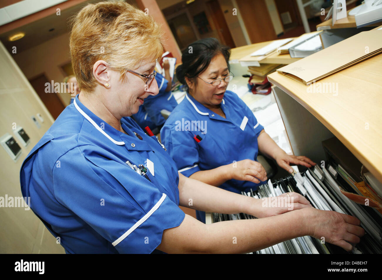 Two hospital nurses in dark blue uniforms filing patient notes in London hospital Stock Photo