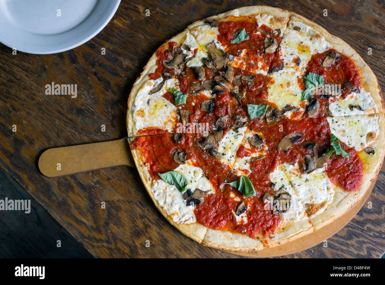 Brick oven pizza with cheese, tomato sauce, basil and mushrooms Stock Photo