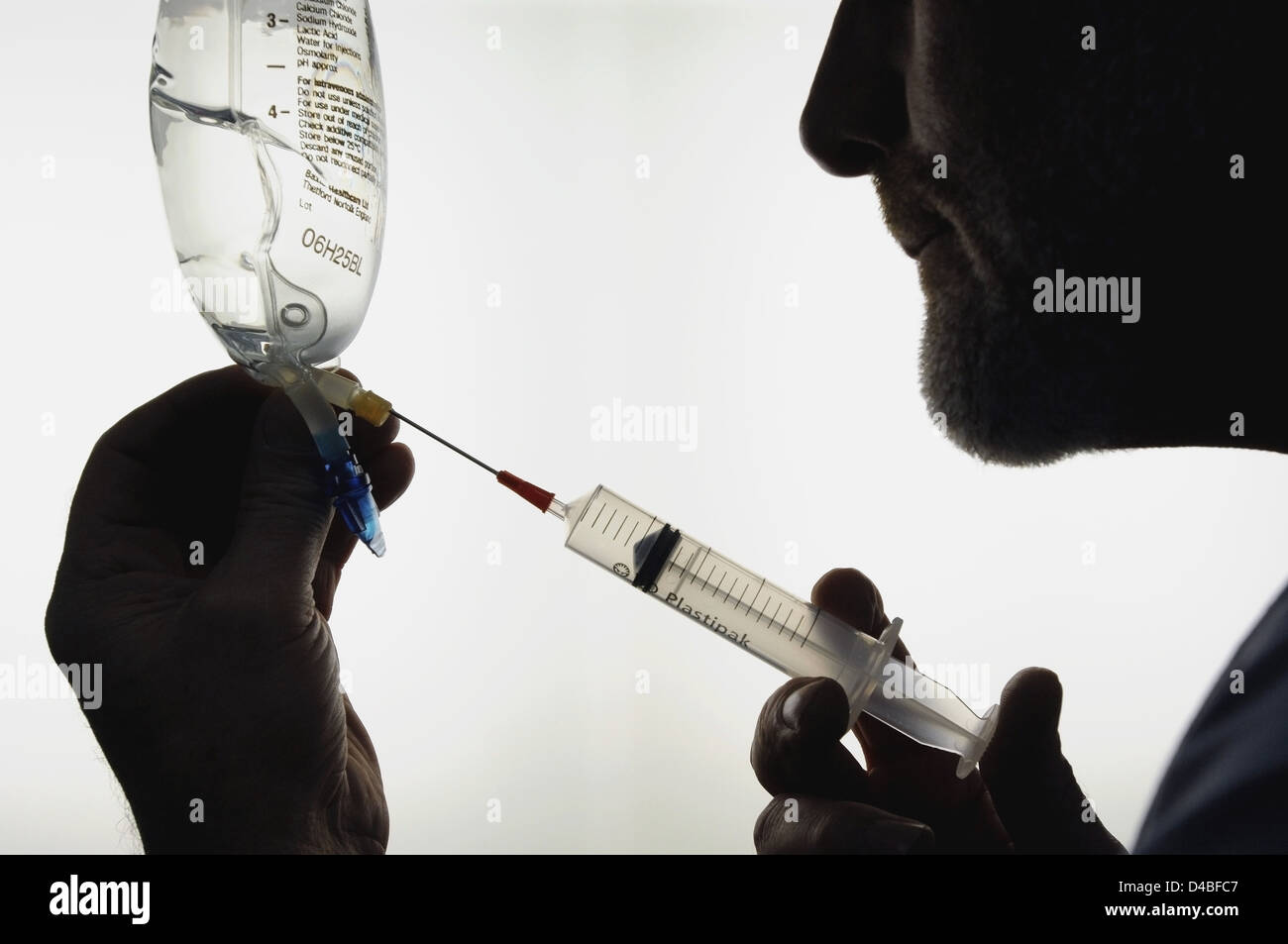 Silhouette of doctor drawing sodium lactate solution into syringe Stock Photo