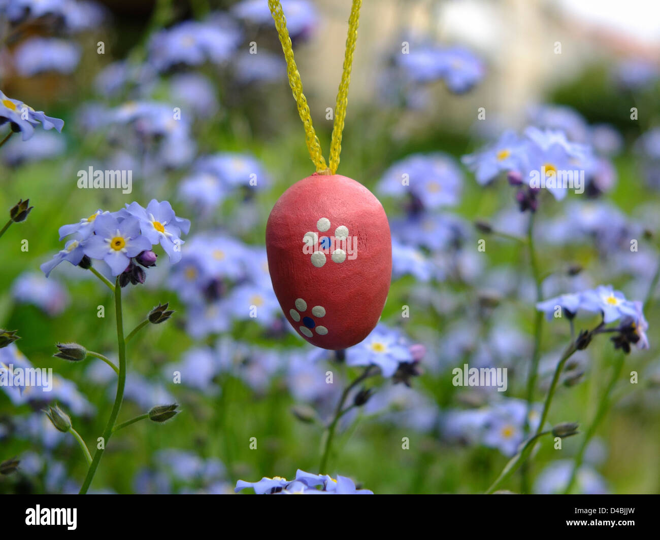 Little red wooden Easter egg in meadow in the spring season Stock Photo