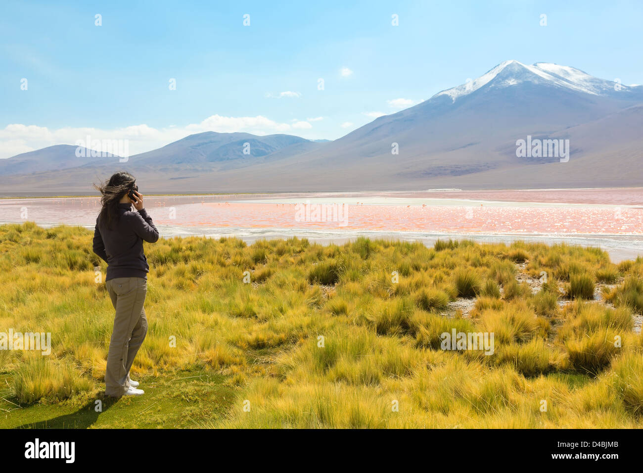 Girl speaking on the phone on the shore of Laguna Colorada, Bolivia Stock Photo