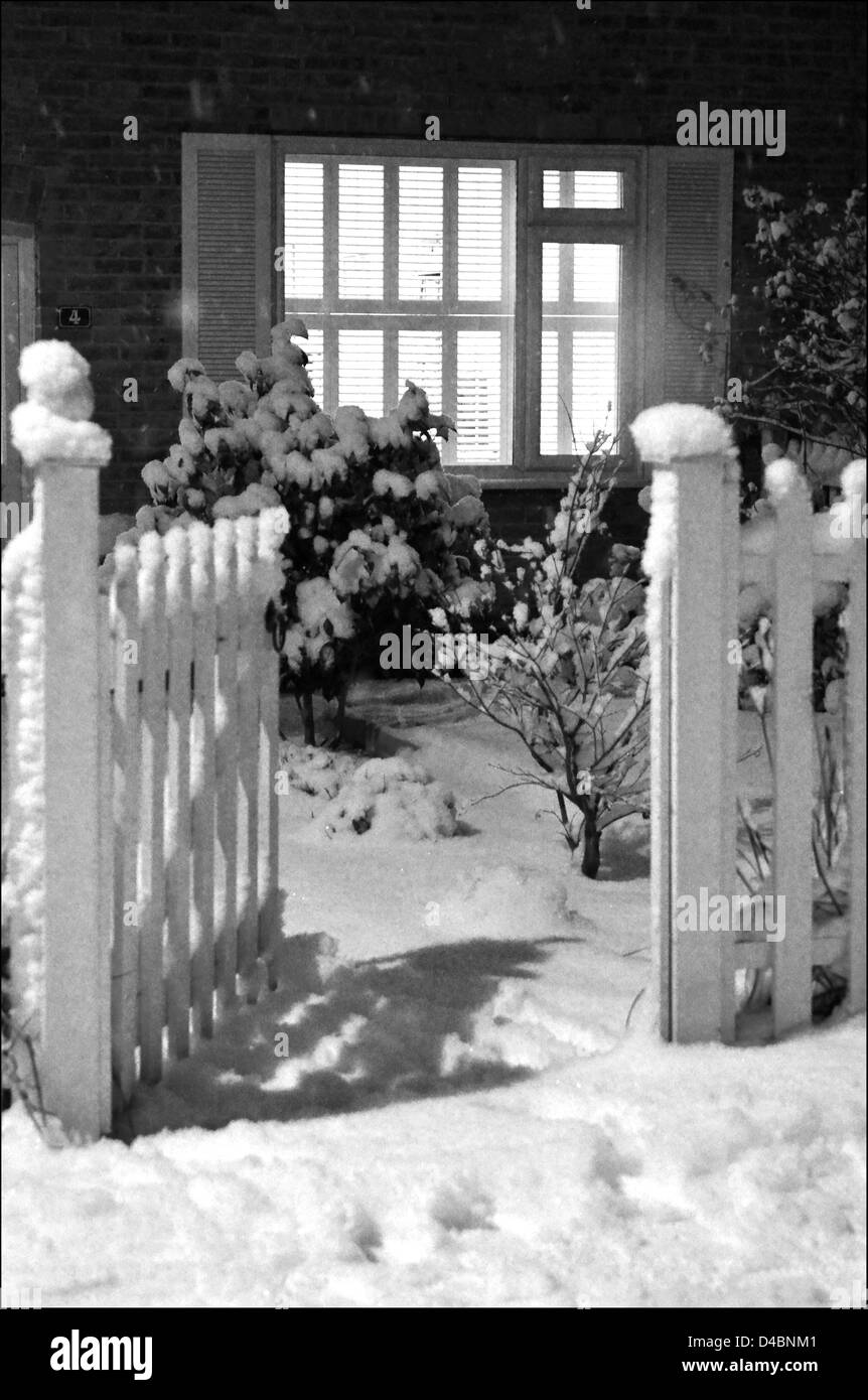 A GARDEN GATE STANDS OPEN READY TO WELCOME FAMILY AND VISITORS ON A SNOWY NIGHT Stock Photo