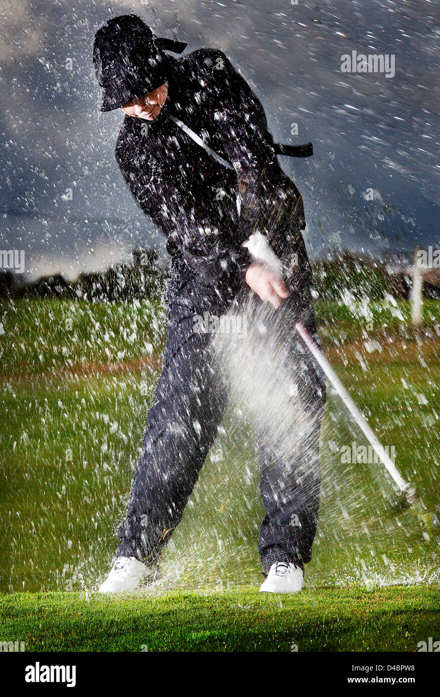 A European male age 20-25 playing golf in the rain Stock Photo