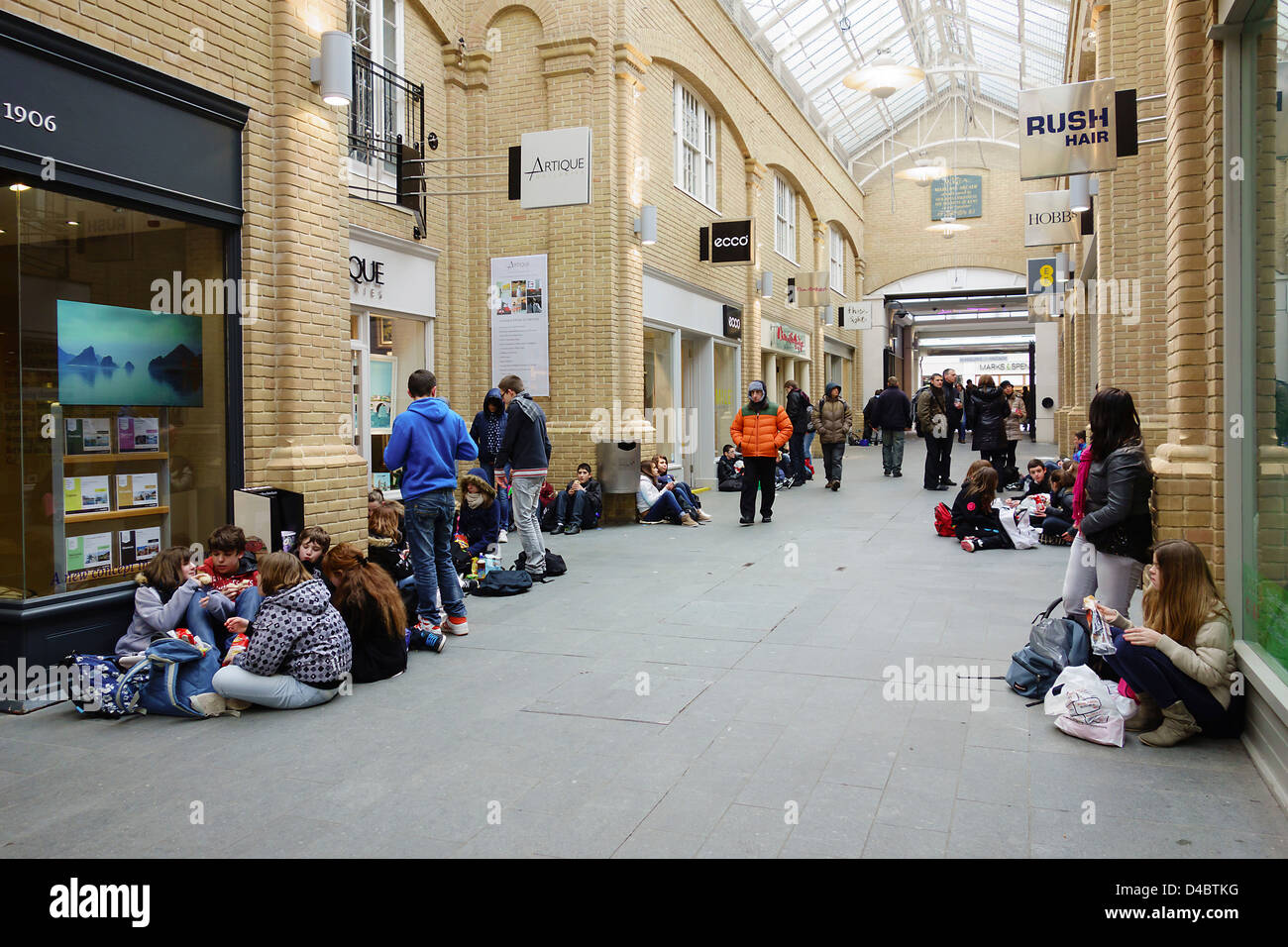 Students on school outing eating lunch in the Marlowe Arcade Canterbury Kent England. Stock Photo