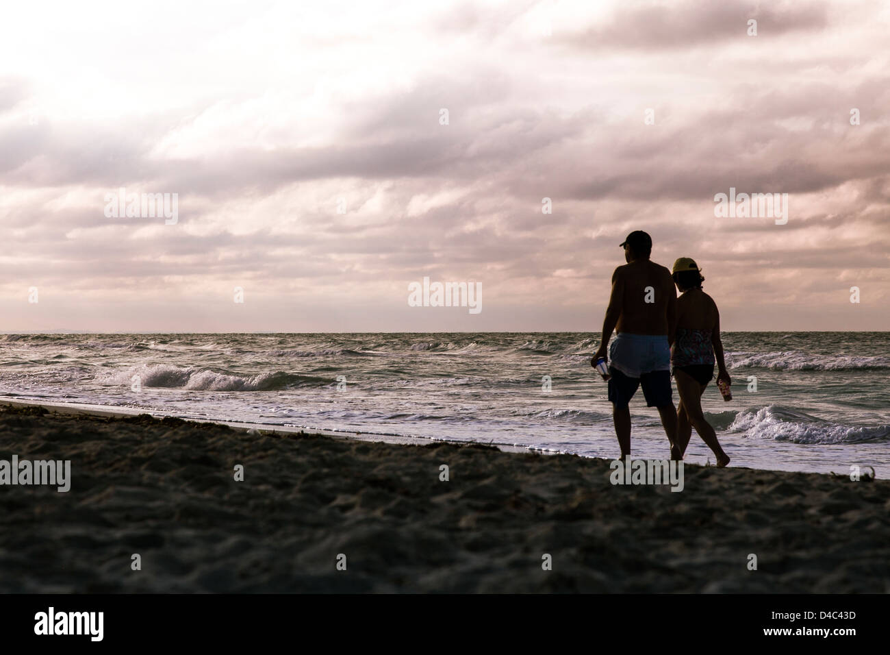 A couple in silhouette walking on the beach Stock Photo - Alamy