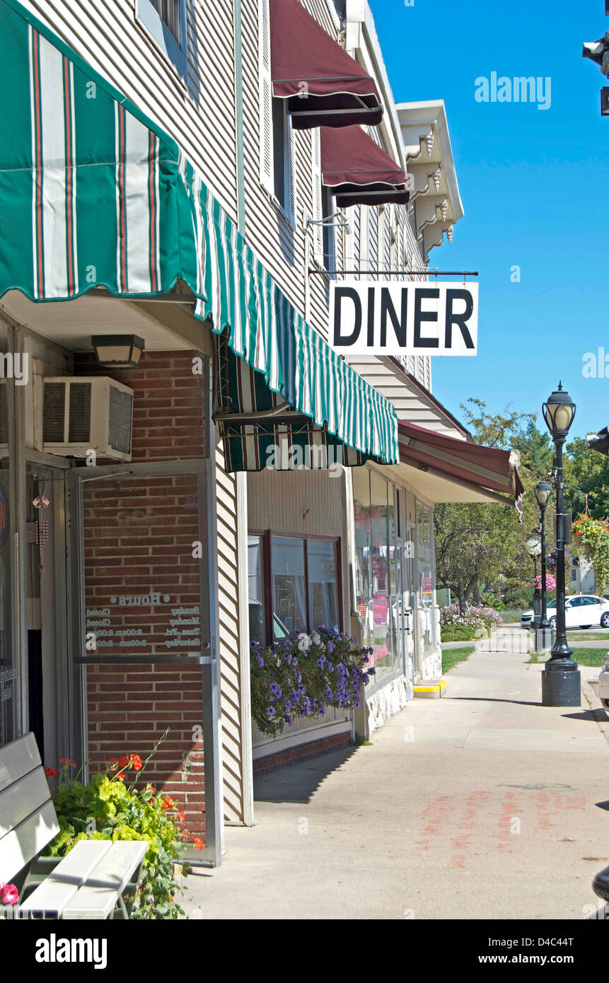Diner sign jutting out of a small town row of businesses. Includes sidewalk,street lamps,bench,and awnings. Stock Photo