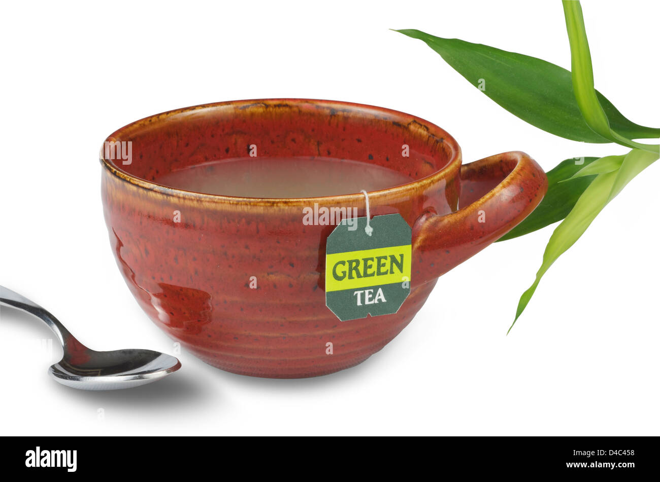Cup of green tea in a red modern tea cup with spoon and green bamboo sprig. Stock Photo