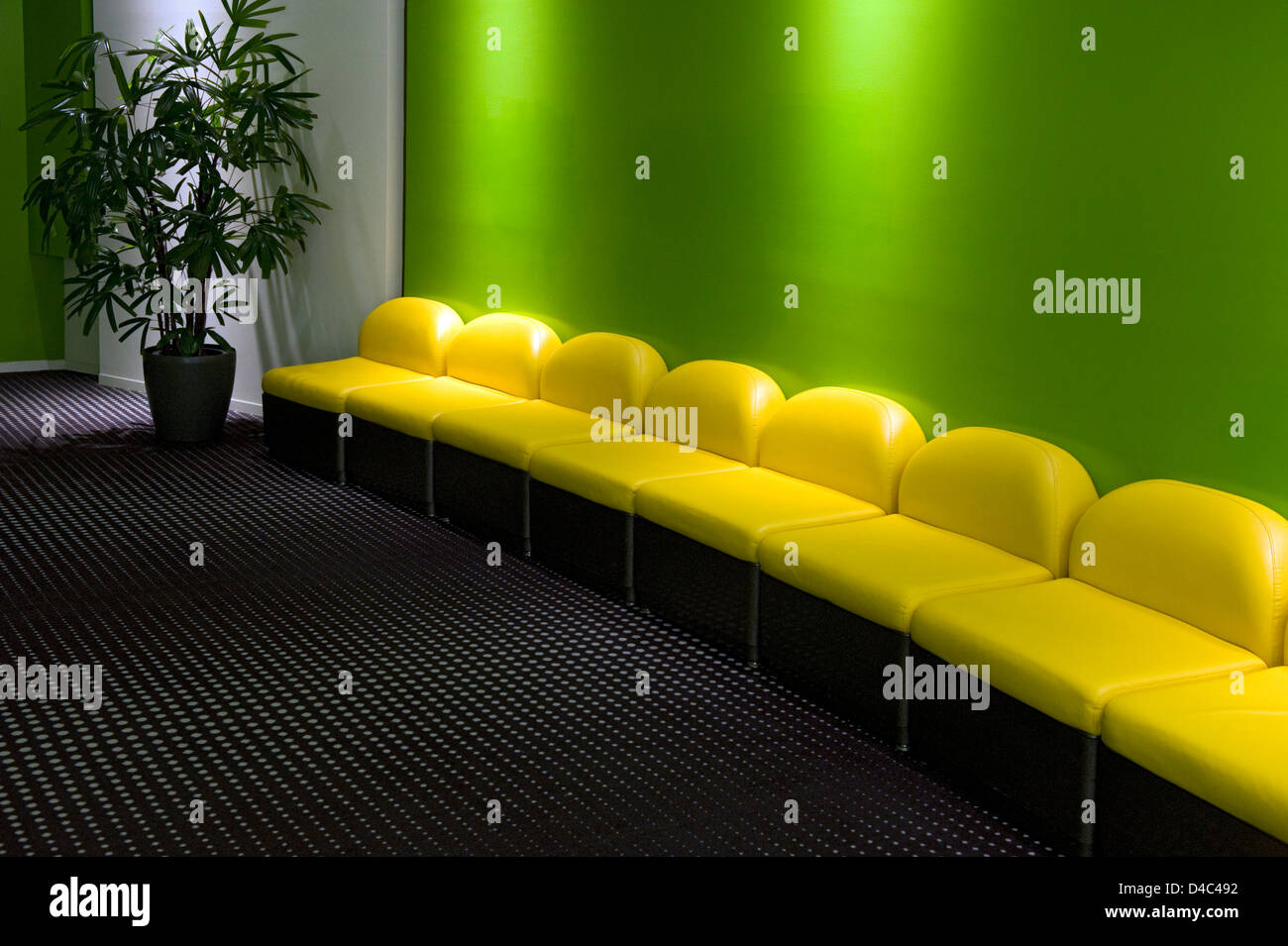 Complementary colored bright yellow curved bench seat against a lime green wall creates a stunning composition, a study in shape Stock Photo