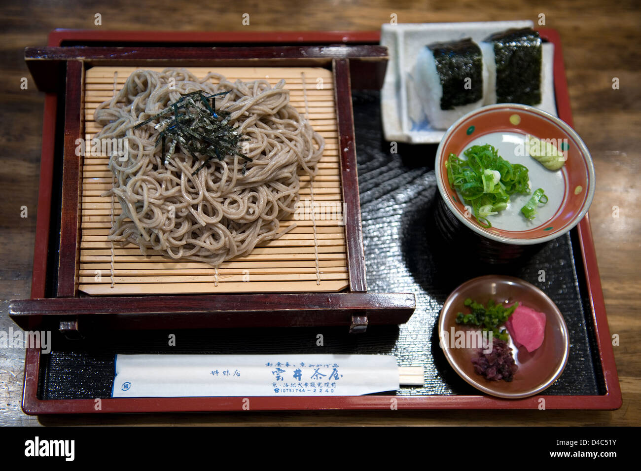 Lunch, Japanese style, includes cold soba noodles with nori, otsukemono pickles and two onigiri rice balls. Stock Photo