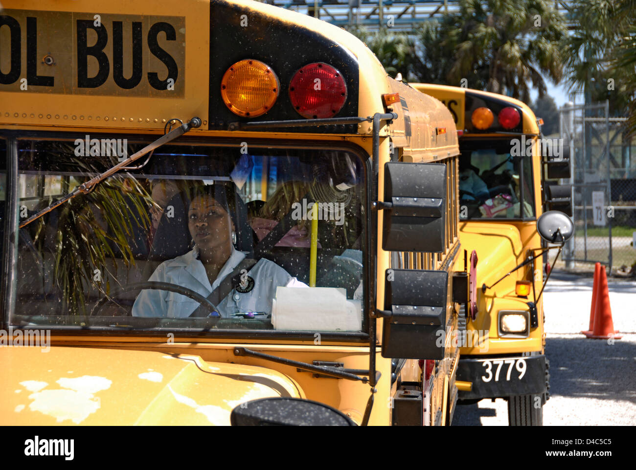 Black woman drives school bus followed by several other buses leaving