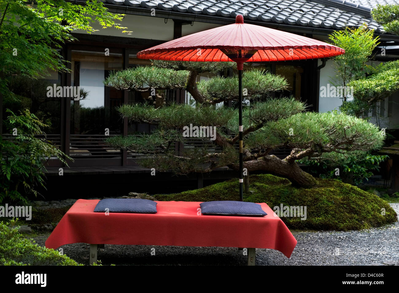 A quintessential Japanese garden scene with red paper umbrella and velvet resting bench, Ohara, Kyoto, Japan Stock Photo