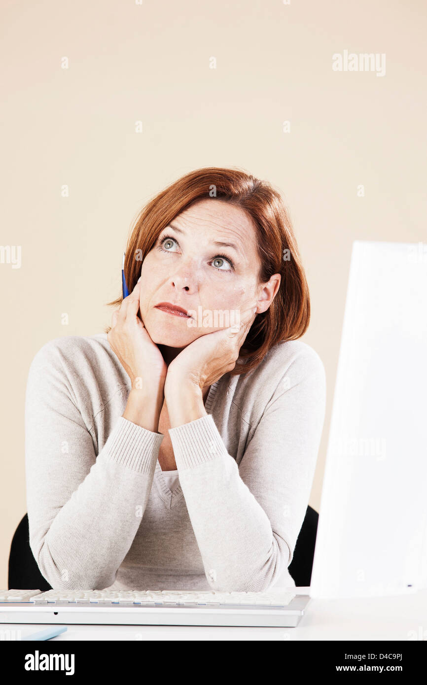 Woman sitting pensively at computer Stock Photo
