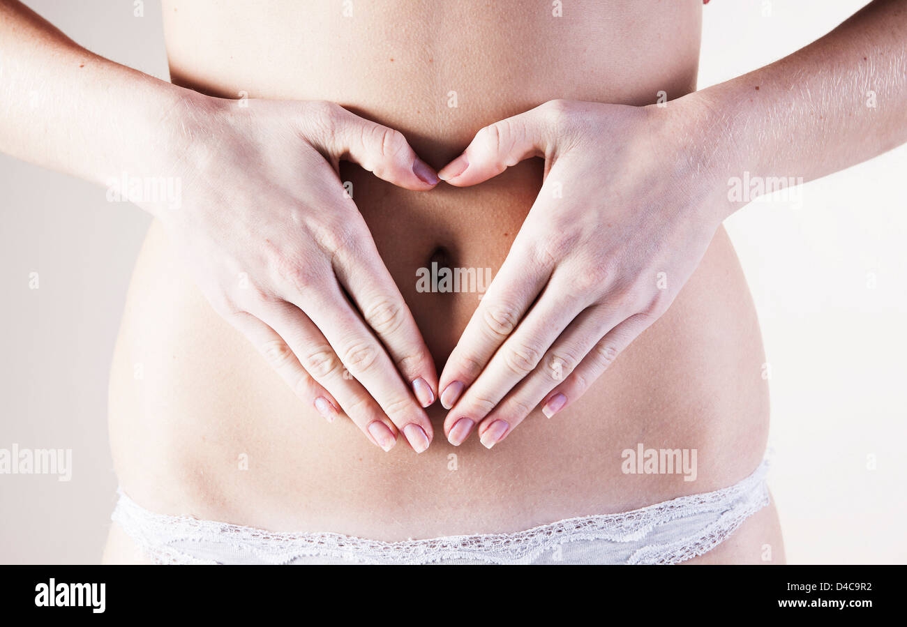 Hands of a young woman forming a heart on her belly Stock Photo