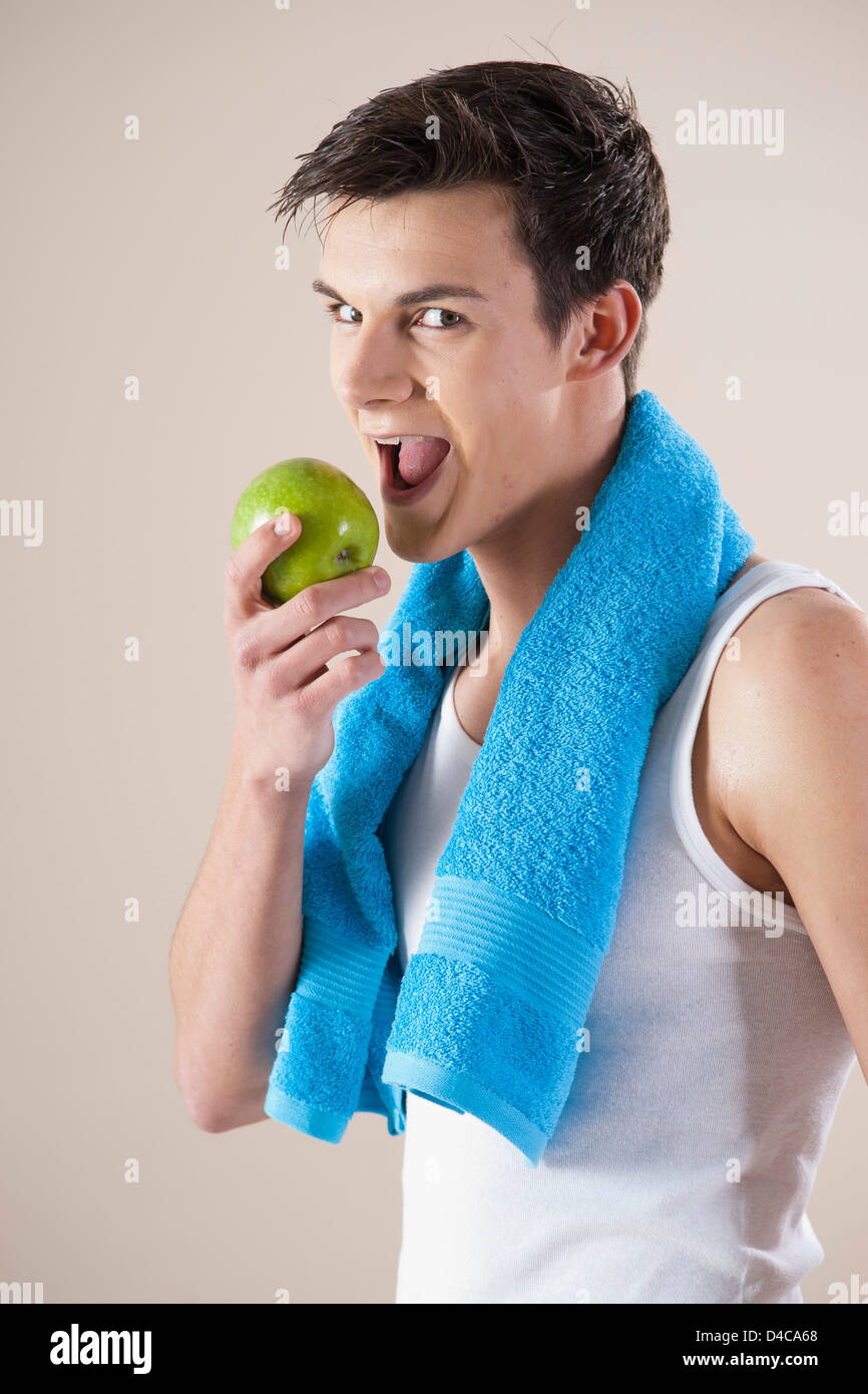 young smiling man bites in an apple Stock Photo