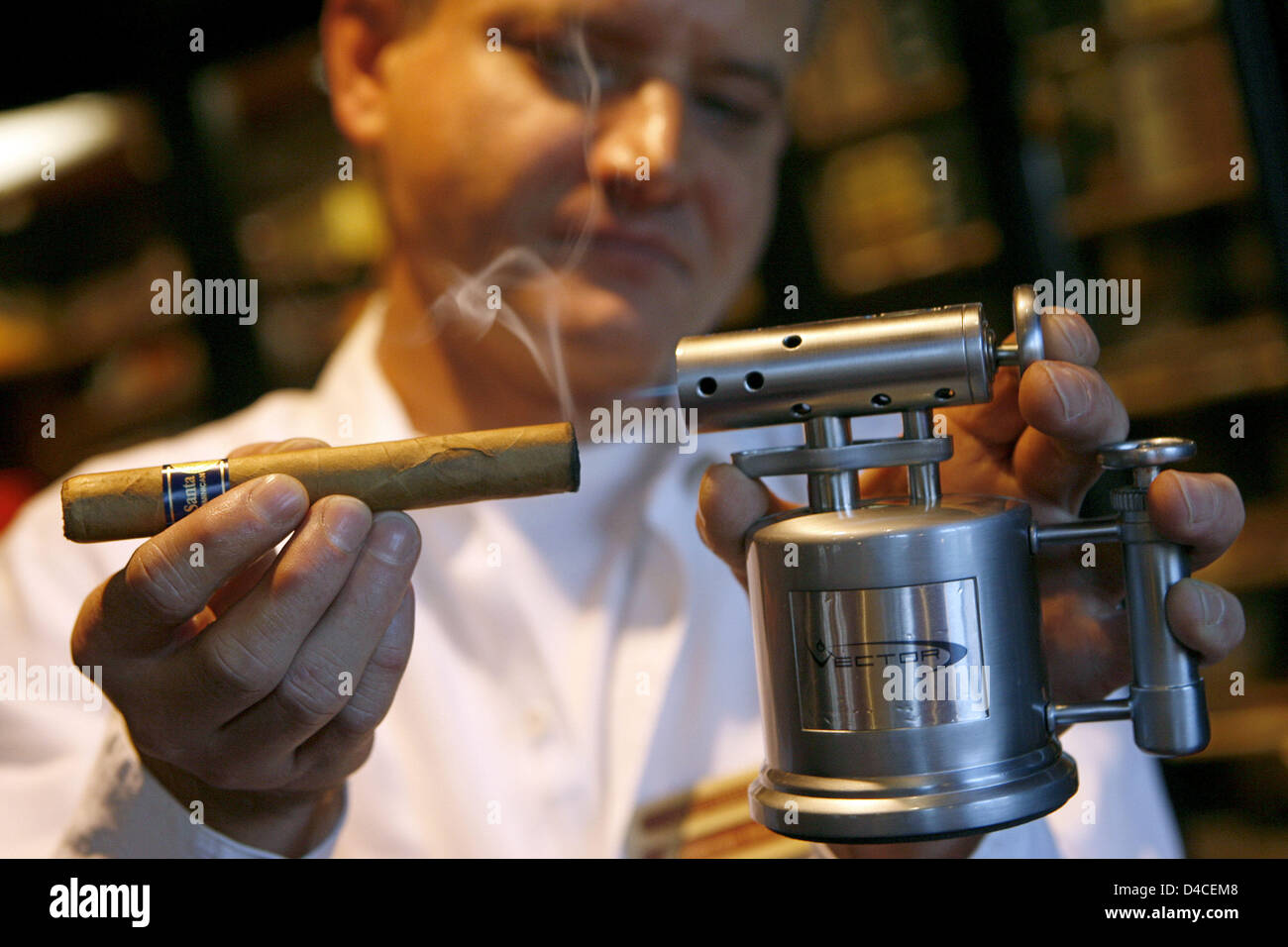 A staff member of cigar lounge 'Casa del Habano' skillfully lights a cigar with an appropriate lighter in the lounge's humidor in Nuremberg, Germany, 16 January 2008. The two-storey lounge in colonial style was opened in downtown Nuremberg in 2006. Photo: Daniel Karmann Stock Photo