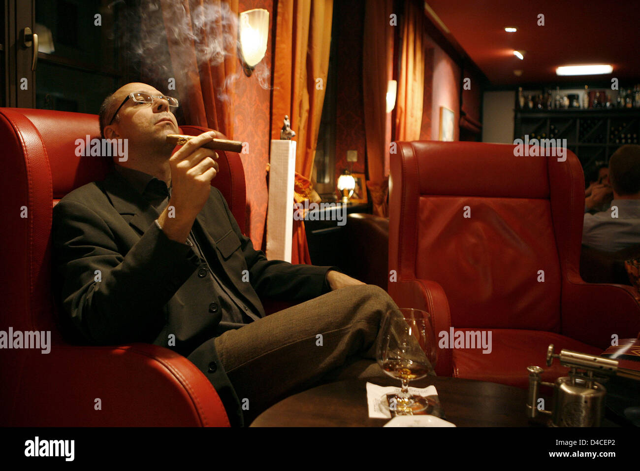 A Man Enjoys A Decent Cigar And A Nice Glass Of Cognac At Cigar
