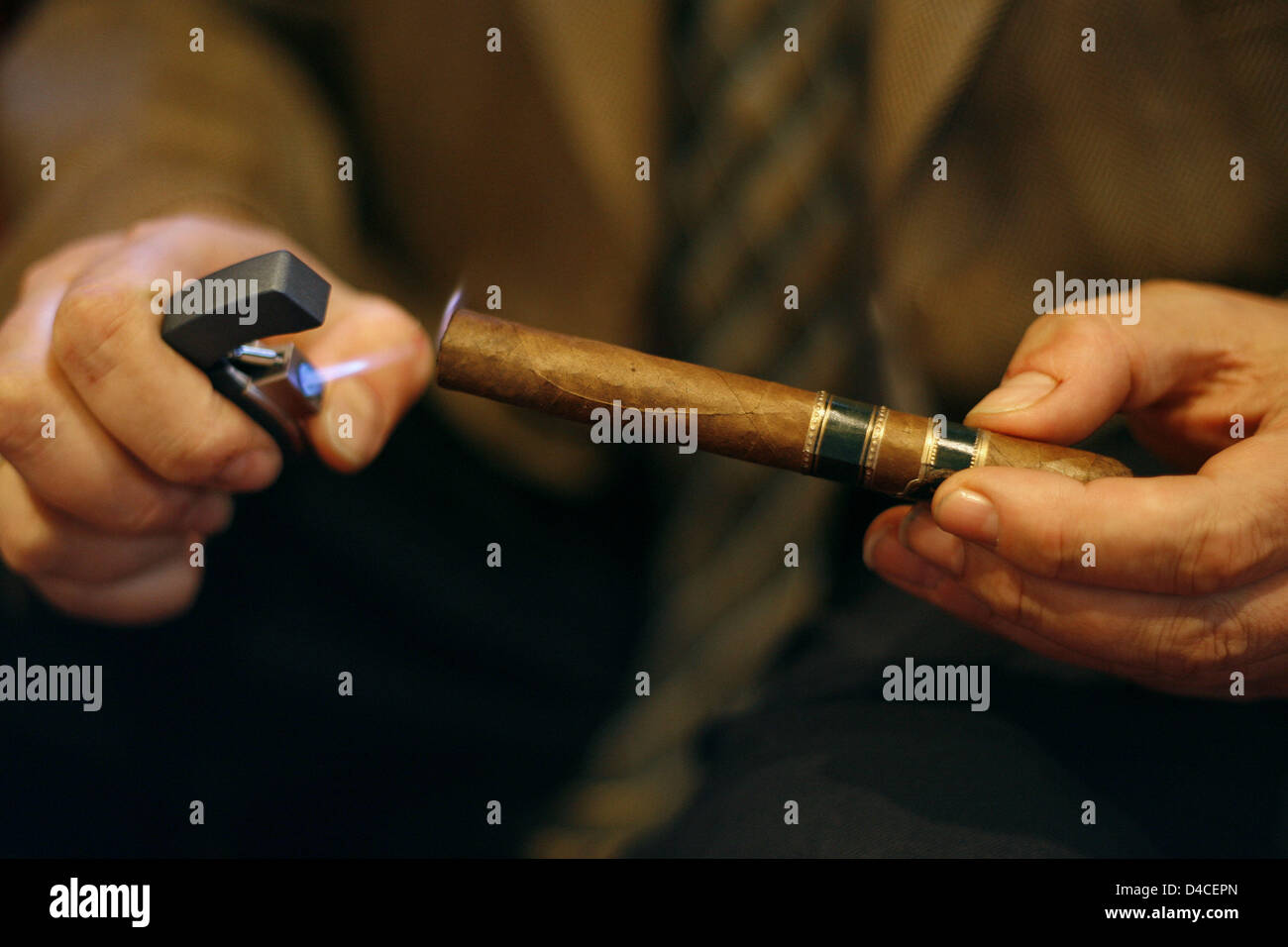 A staff member of cigar lounge 'Casa del Habano' skillfully lights a cigar with an appropriate lighter in the lounge's humidor in Nuremberg, Germany, 16 January 2008. The two-storey lounge in colonial style was opened in downtown Nuremberg in 2006. Photo: Daniel Karmann Stock Photo