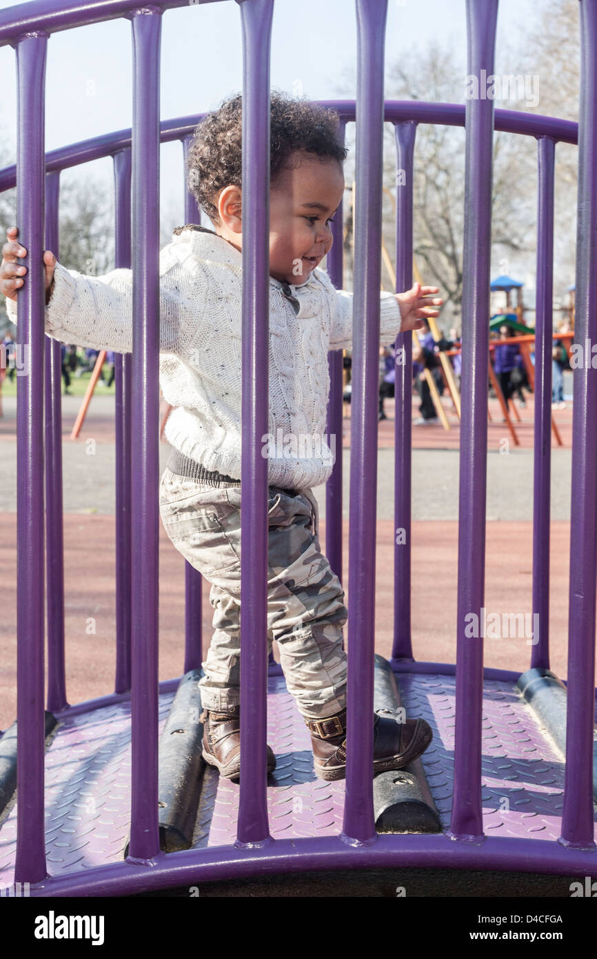 mixed race toddler holding onto purple railings walking over bridge ...