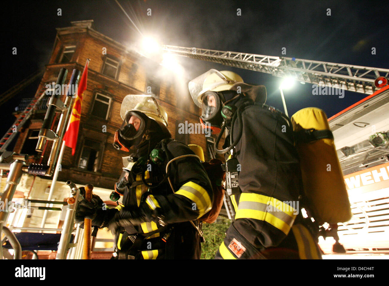 Firemen use turntable ladders to fight a fire at a multi-family house in Ludwigshafen, Germany, 03 February 2008. Over 60 people were injured in the incident, including children and police officials who meant to rescue inhabitants. The fire's source is yet undetermined, as the area is still largely cordoned off. Photo: BORIS ROESSLER Stock Photo
