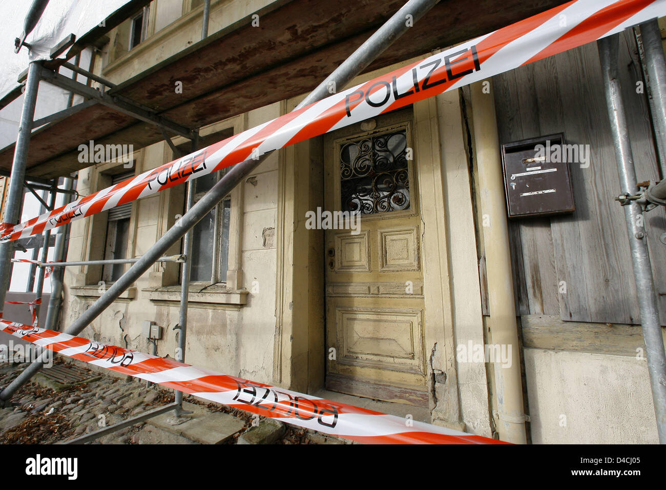 A house parcially covered by a scaffolding is cordoned off by police tape in the Mauer street in Nauen, Germany, 06 February 2008. The house is the discovery site of a dead baby, who was found in a plastic bag in an open cellar by the house's owner on an inspection tour. After the discovery the police searches for the mother of the dead infant. An autopsy was ordered for the 06 Feb Stock Photo