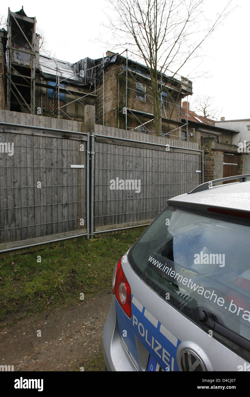 A police car parks in front of a  house parcially covered by a scaffolding in the Mauer street in Nauen, Germany, 06 February 2008. The house is the discovery site of a dead baby, who was found in a plastic bag in an open cellar by the house's owner on an inspection tour. After the discovery the police searches for the mother of the dead infant. An autopsy was ordered for the 06 Fe Stock Photo