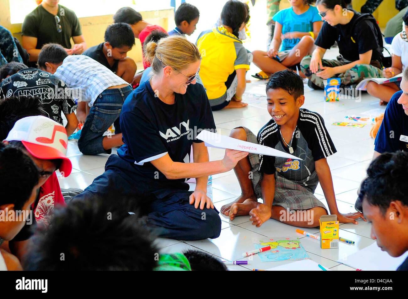 New Zealand Defence Force Lt. Cmdr. Kerry Climo Gives an Indonesian Boy a Paper Airplane Stock Photo