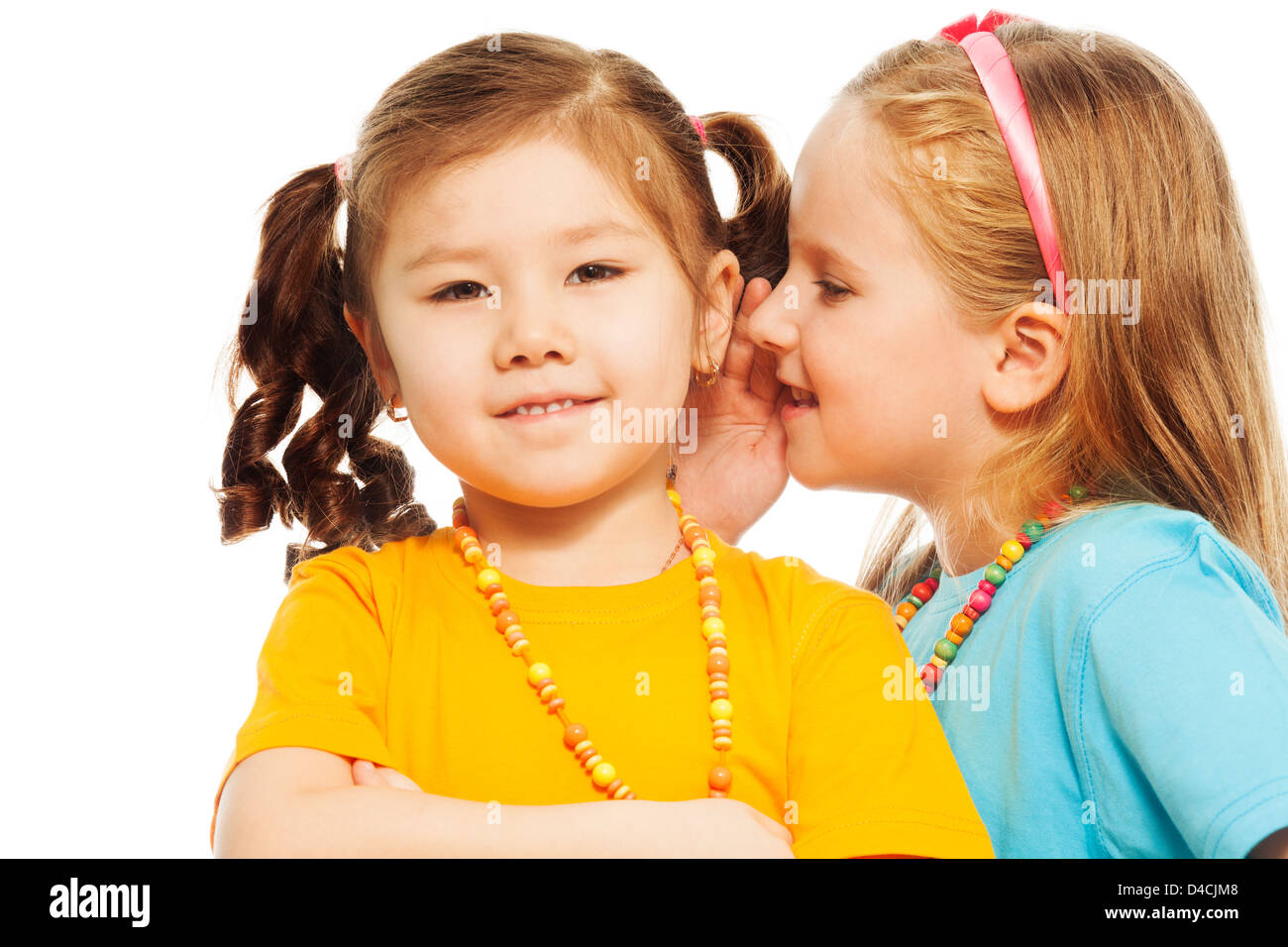 Close portrait of two little 6-7 years old Asian and Caucasian girls whisper telling secrets mouse to ear, isolated on white Stock Photo