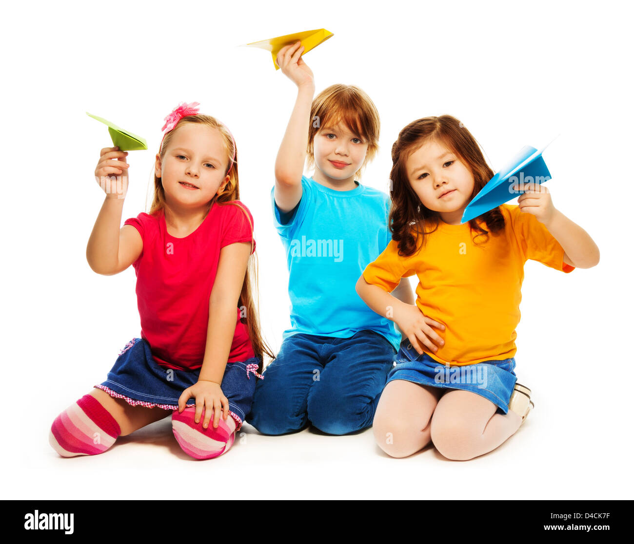 Three little kids sitting with colorful paper plane, boy and girl, Caucasian and Asian, isolated on white Stock Photo