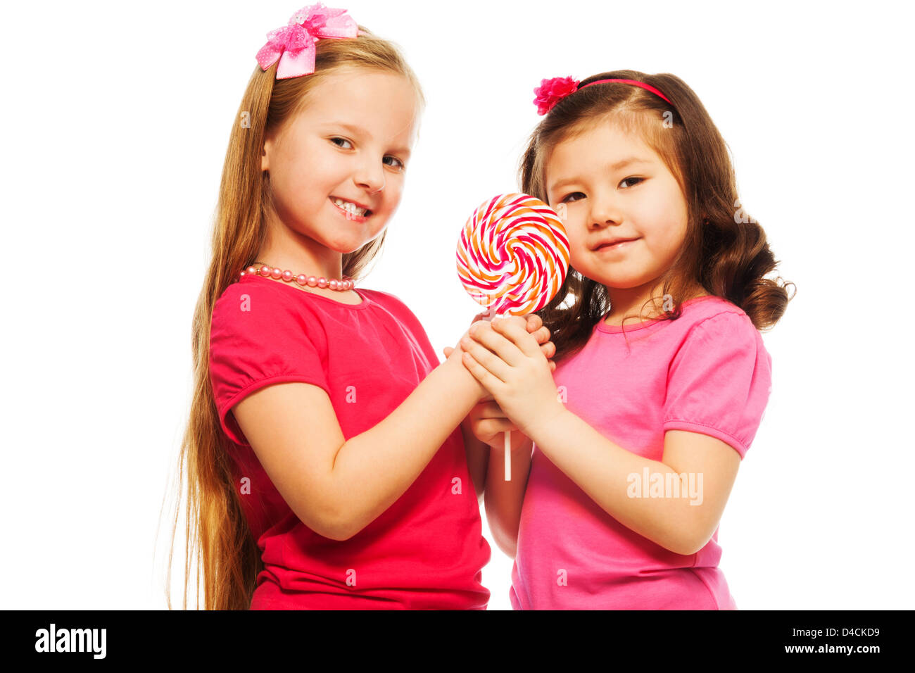 Two girls six seven years old holding lollipop and smiling, isolated on white Stock Photo