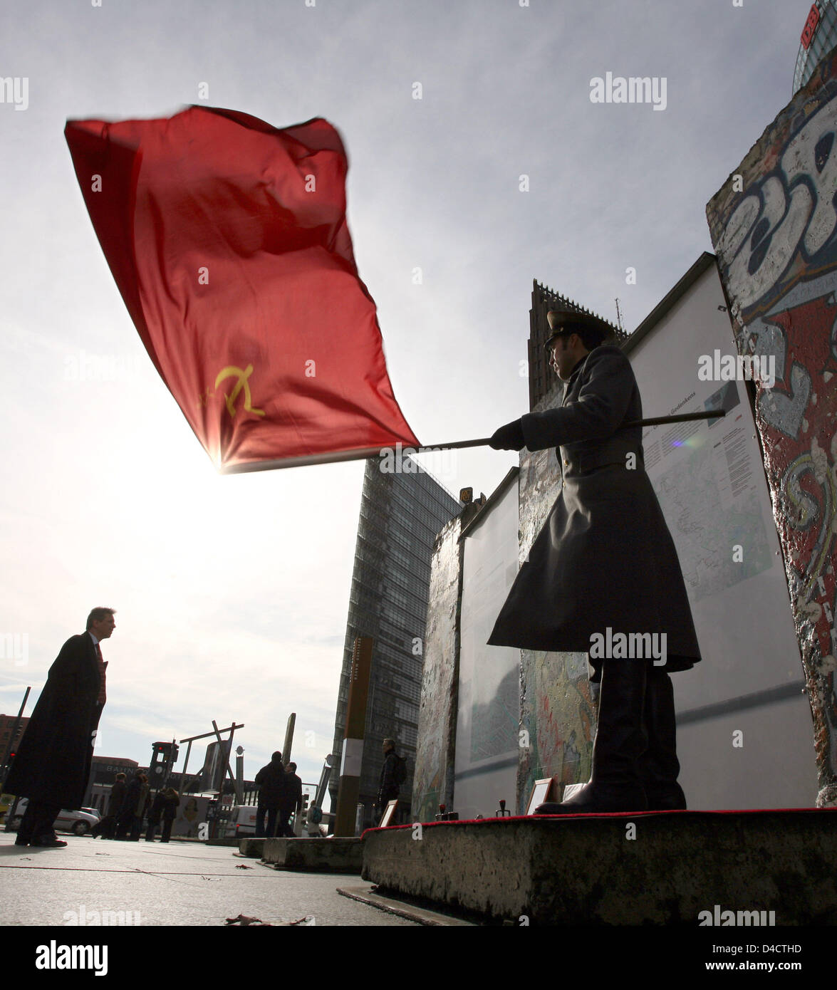 Actor Samir Fuchs, dressed up as a Soviet soldier, waves the Soviet flag in front of the sun at Potsdamer Platz in Berlin, Germany, 20 February 2008. Visitors can take pictures of Fuchs at a part of the Berlin Wall. Photo: RAINER JENSEN Stock Photo