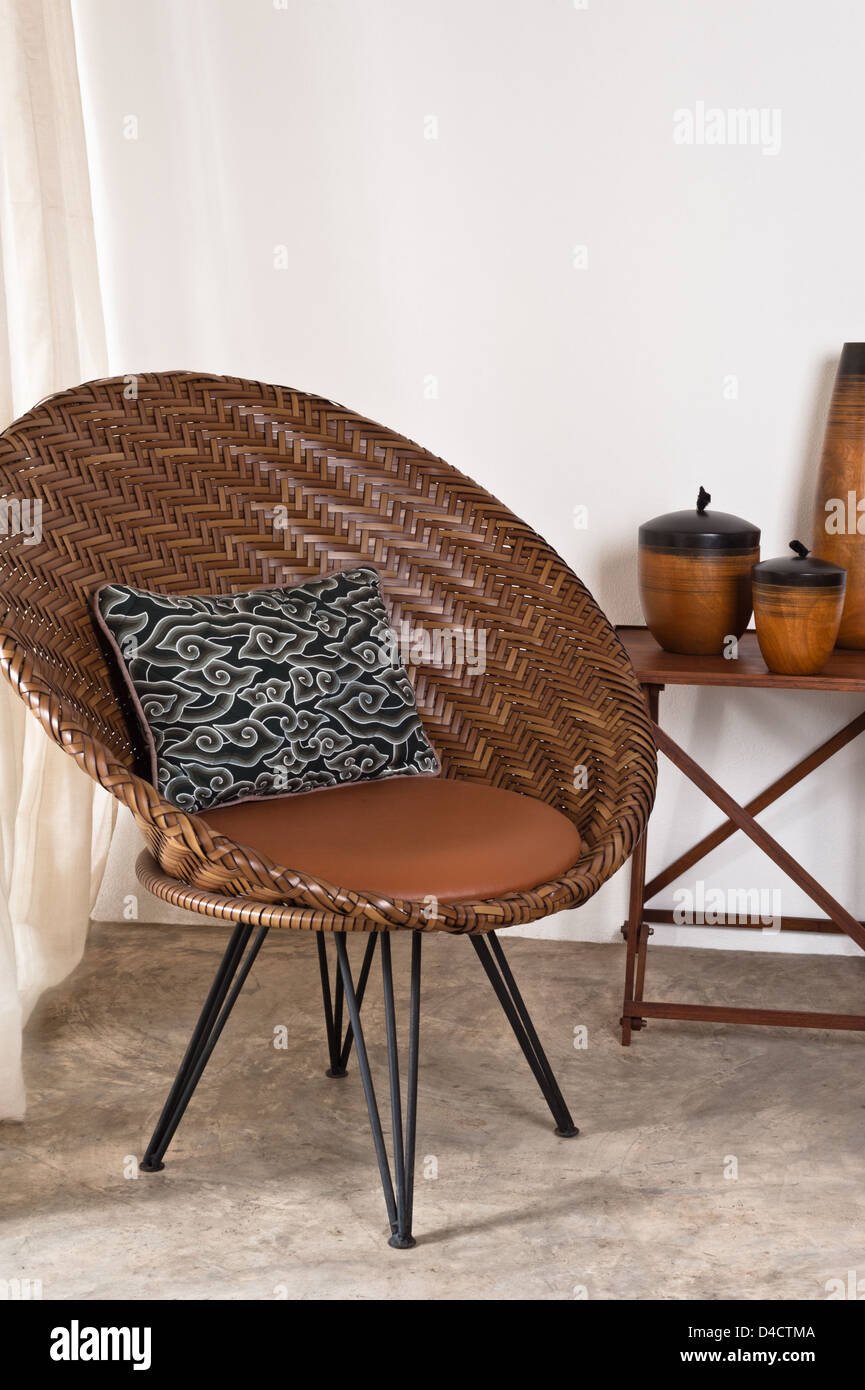 Brown rattan Chair in interior setting in front of a white wall Stock