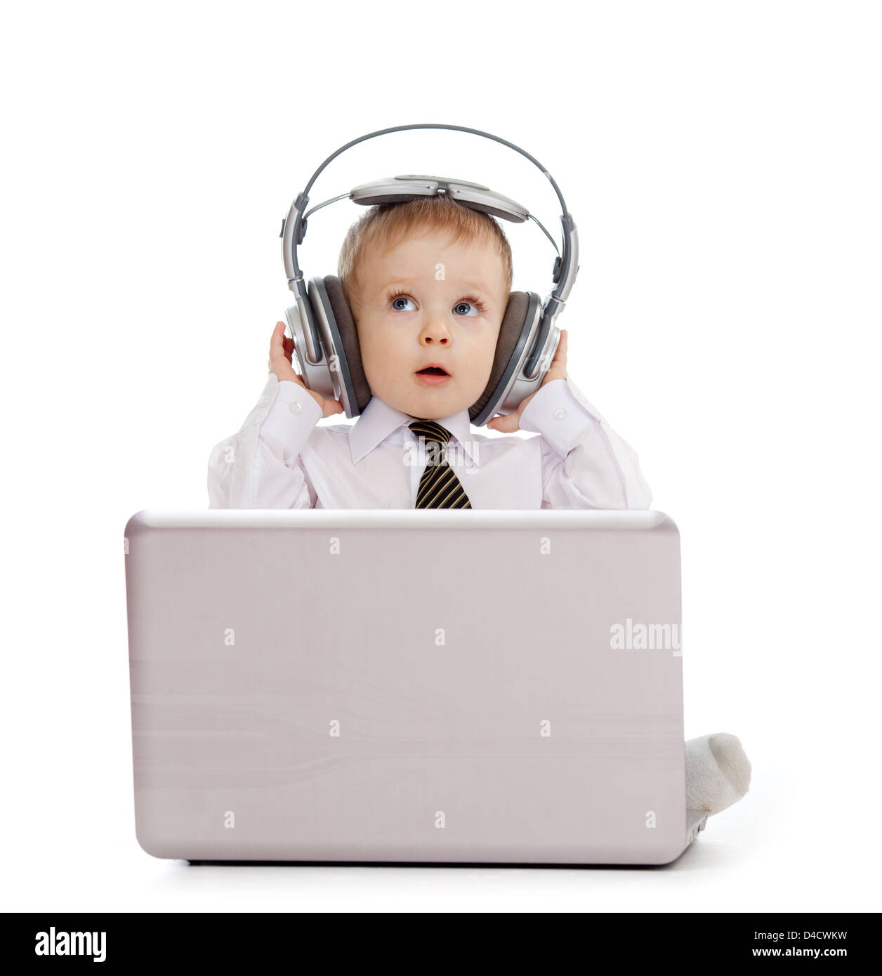 Funny child playing with laptop and listening to music in headphones Stock Photo
