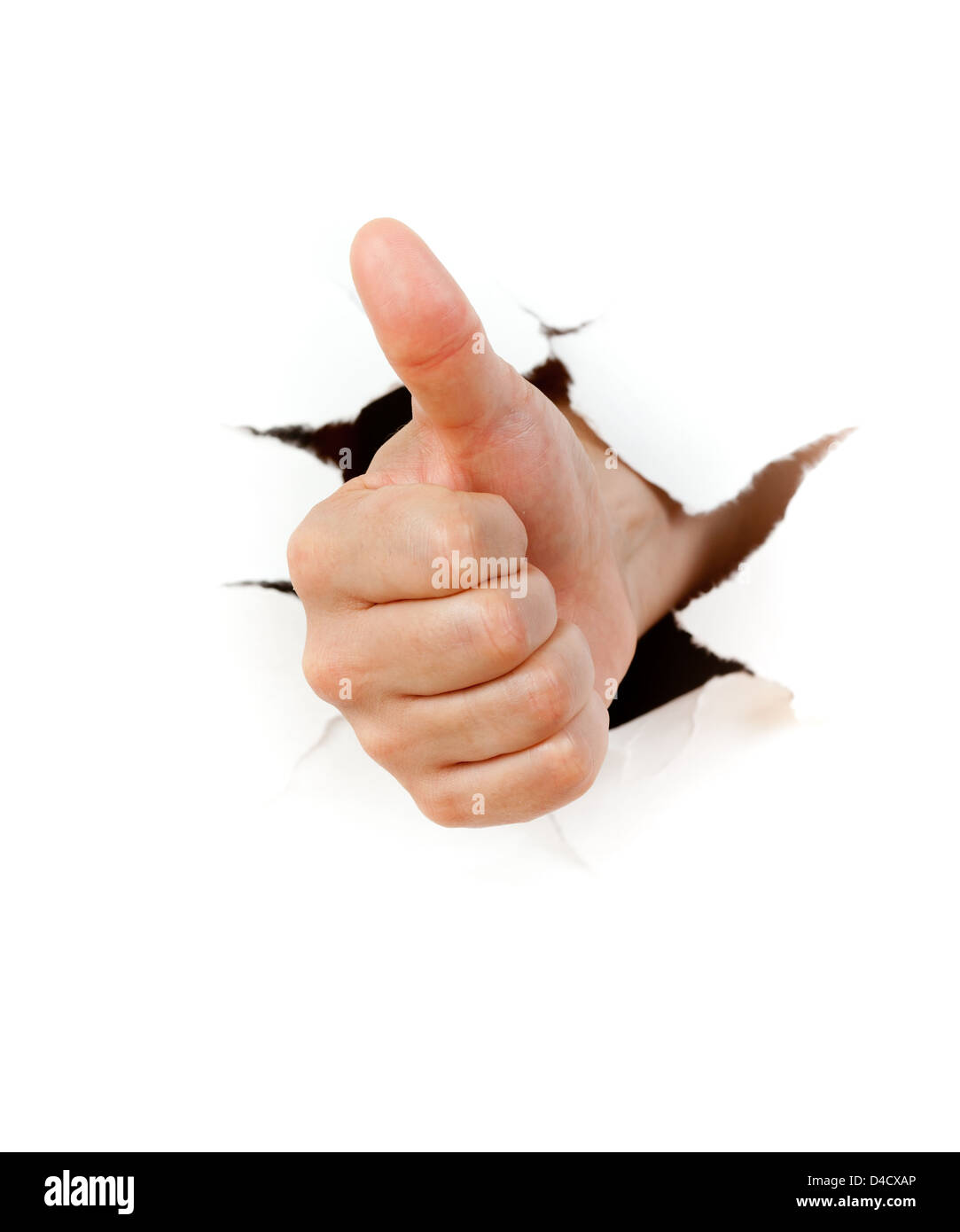 Hand with thumb up through a hole in paper Stock Photo