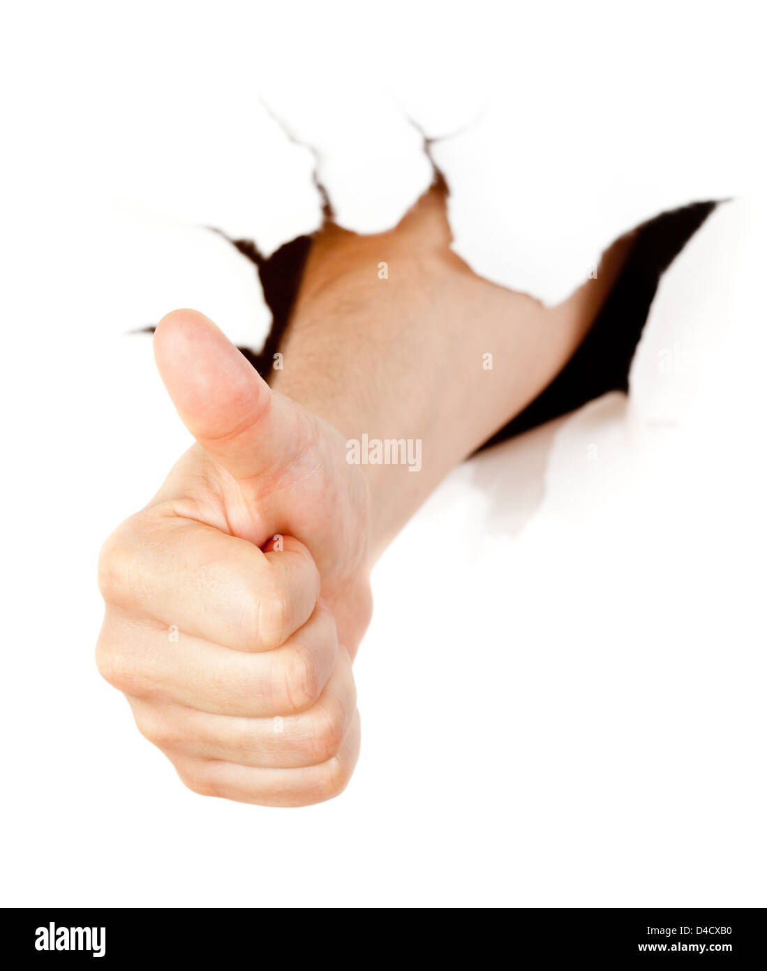 Hand with thumb up through a hole in paper Stock Photo