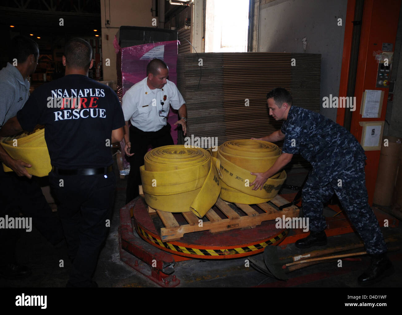 Logistic Specialist 2nd Class (SW) Vitali Toptchenko NSA Naples Lead Fire Inspector Hanz Christian, and Italian National Firefighters Maurazio Patrone and Alessio Storto Load a Pallet of Firefighting Equipment Stock Photo