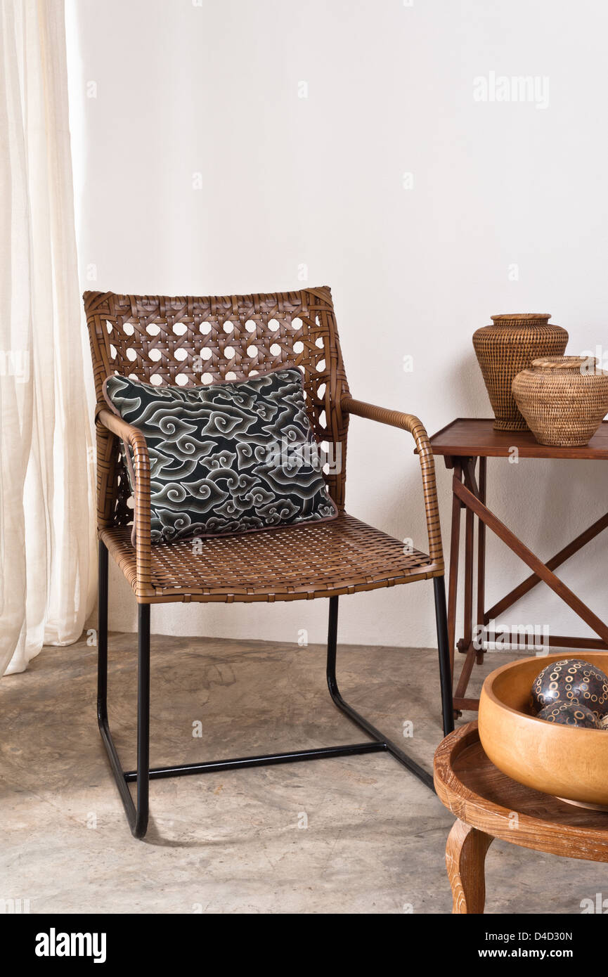 Brown rattan Chair in interior setting in front of a white wall Stock