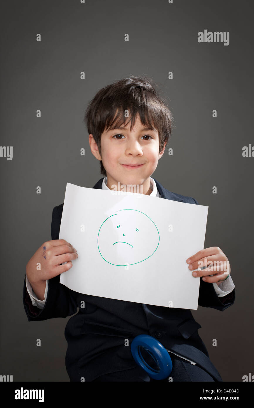 Happy boy with drawing of sad face Stock Photo