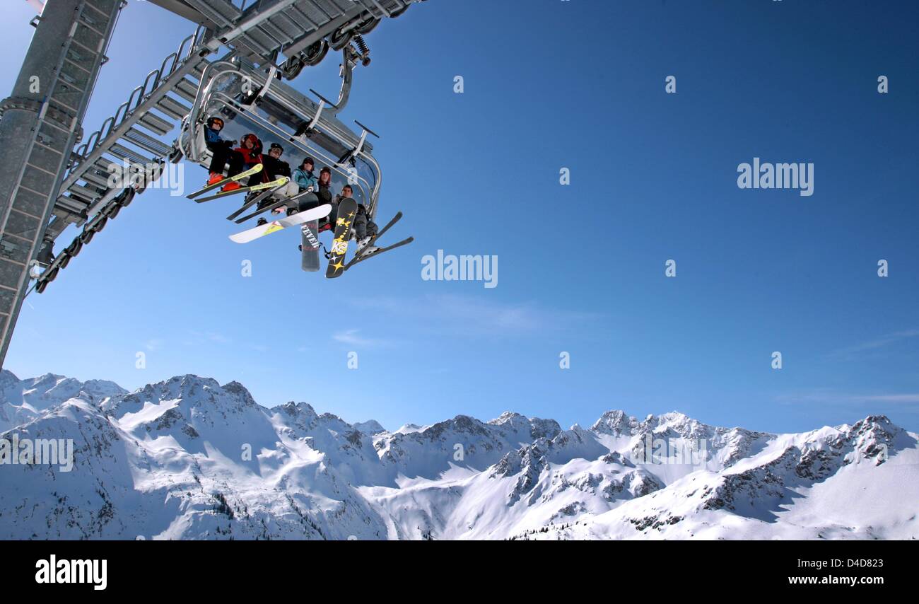 Skiers and snowboarders sit in a chair lift during sunny weather at the ...