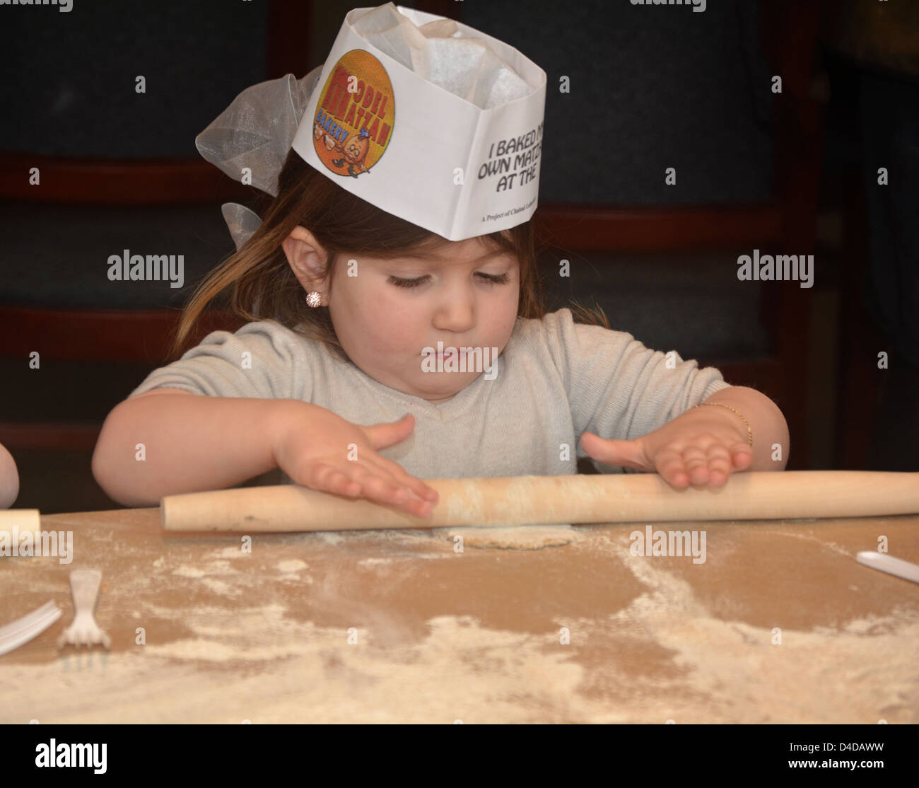5 year old religious Jewish girl learns about Passover by baking Matzah at the Model Matzah Bakery in Brooklyn, New York Stock Photo