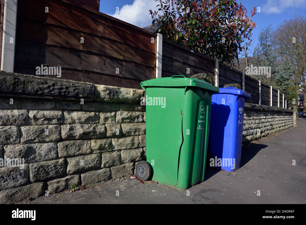 a cracked green wheely bin and a blue wheely bin left on the pavement days after the bins have been emptied Stock Photo