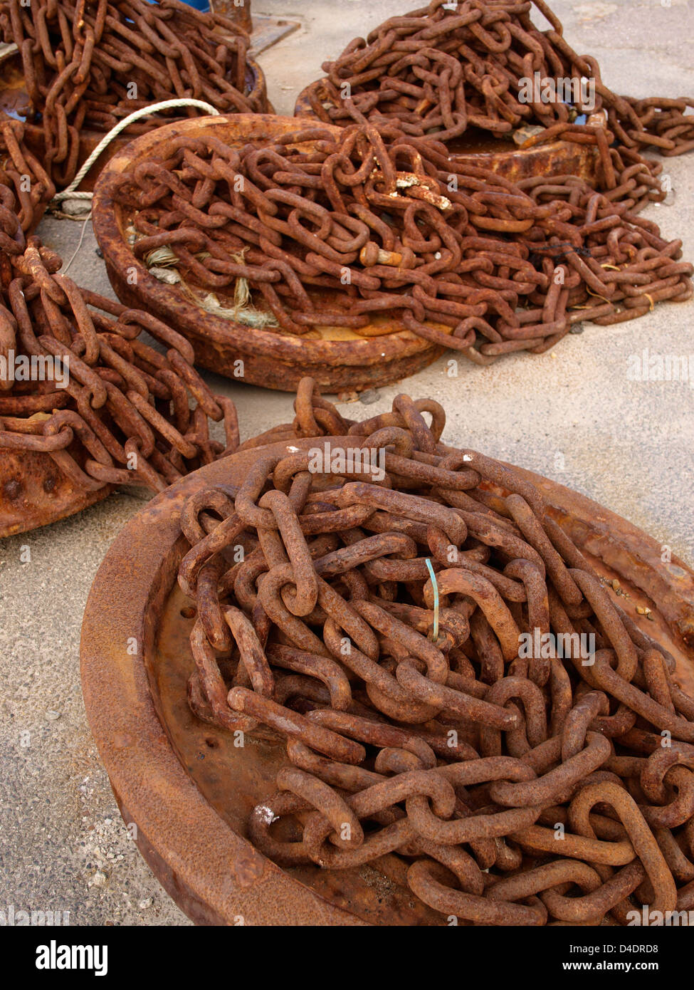 Old train wheels used as weights for holding mooring lines on harbour floor Stock Photo