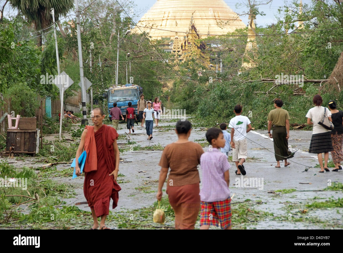 Citizens walk across a street littered with toppled trees and other debris in Yangon, Myanmar, 5 May 2008. International aid has begun after cyclone 'Nargis' devastated Myanmar, though the exact situation in the country, which is isolated from the outside world by the military junta, remains unclear. Most traffic routes are blocked, Myanmar's government assumes that more than 15,00 Stock Photo