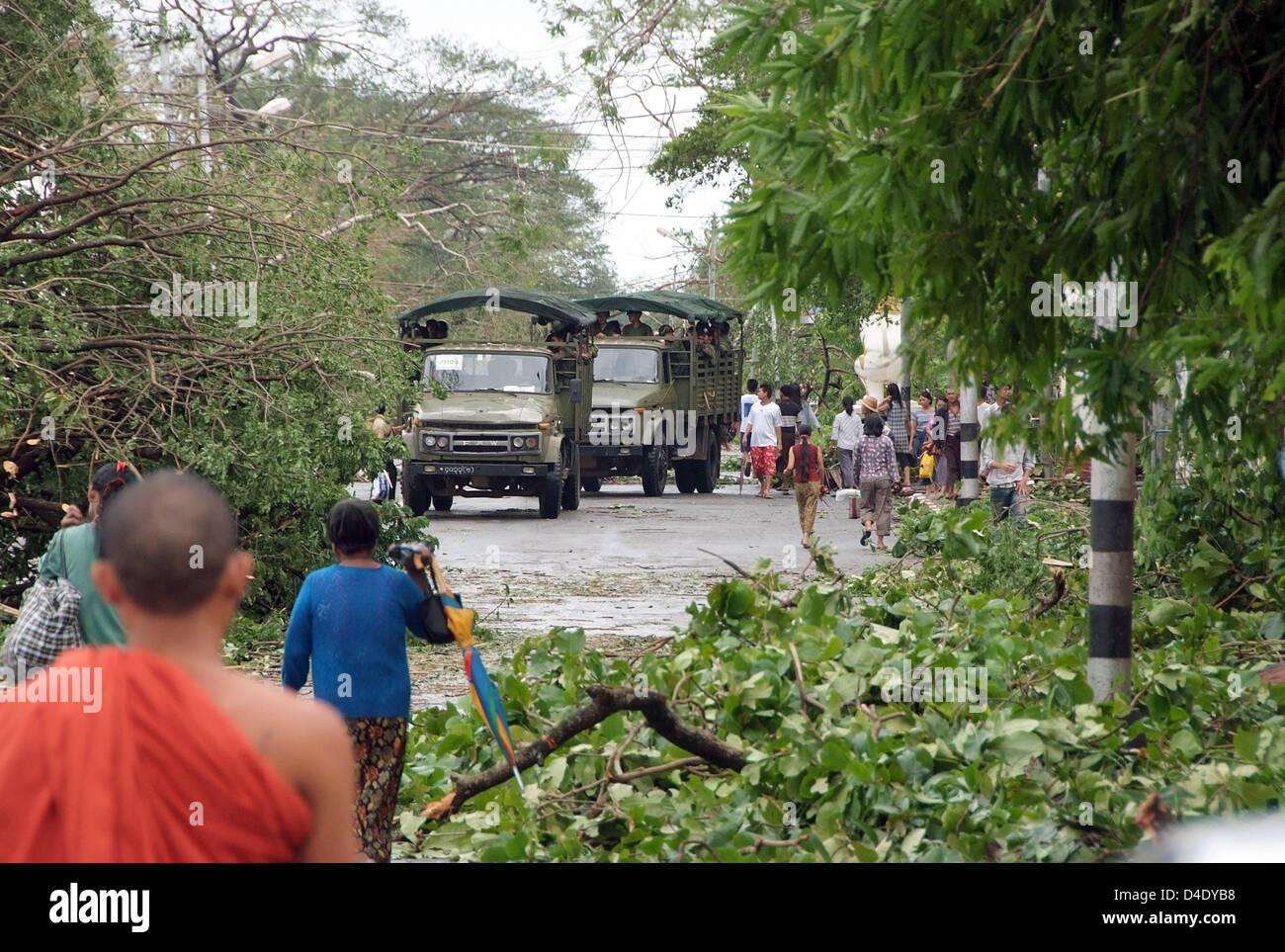 Citizens and military lorries work their way through trees and other debris blocking a street in Yangon, Myanmar, 5 May 2008. International aid has begun after cyclone 'Nargis' devastated Myanmar, though the exact situation in the country, which is isolated from the outside world by the military junta, remains unclear. Most traffic routes are blocked, Myanmar's government assumes t Stock Photo