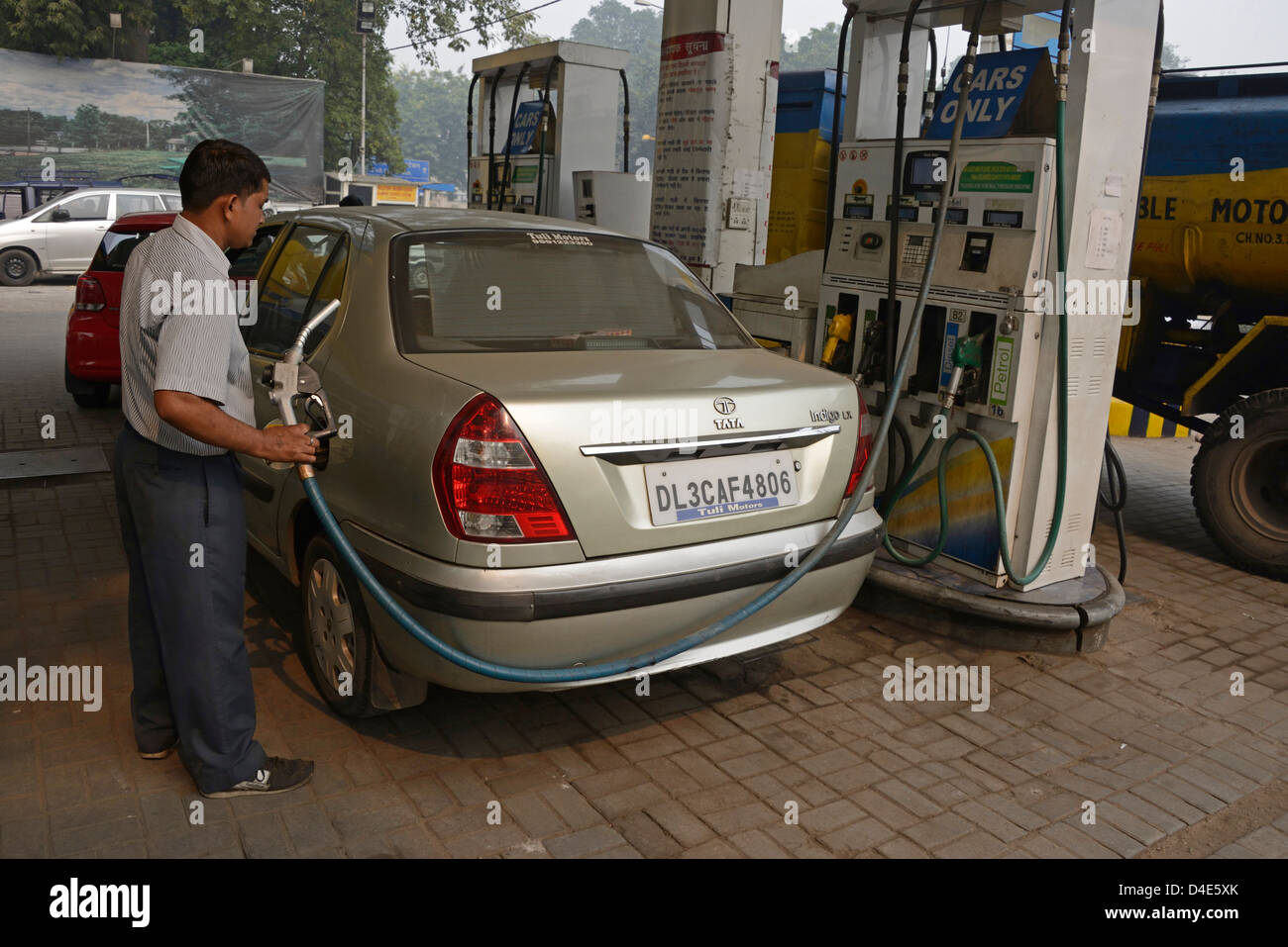 A garage fuel attendant filling up with fuel at a Bharat petrol station in Old Delhi, India. Stock Photo