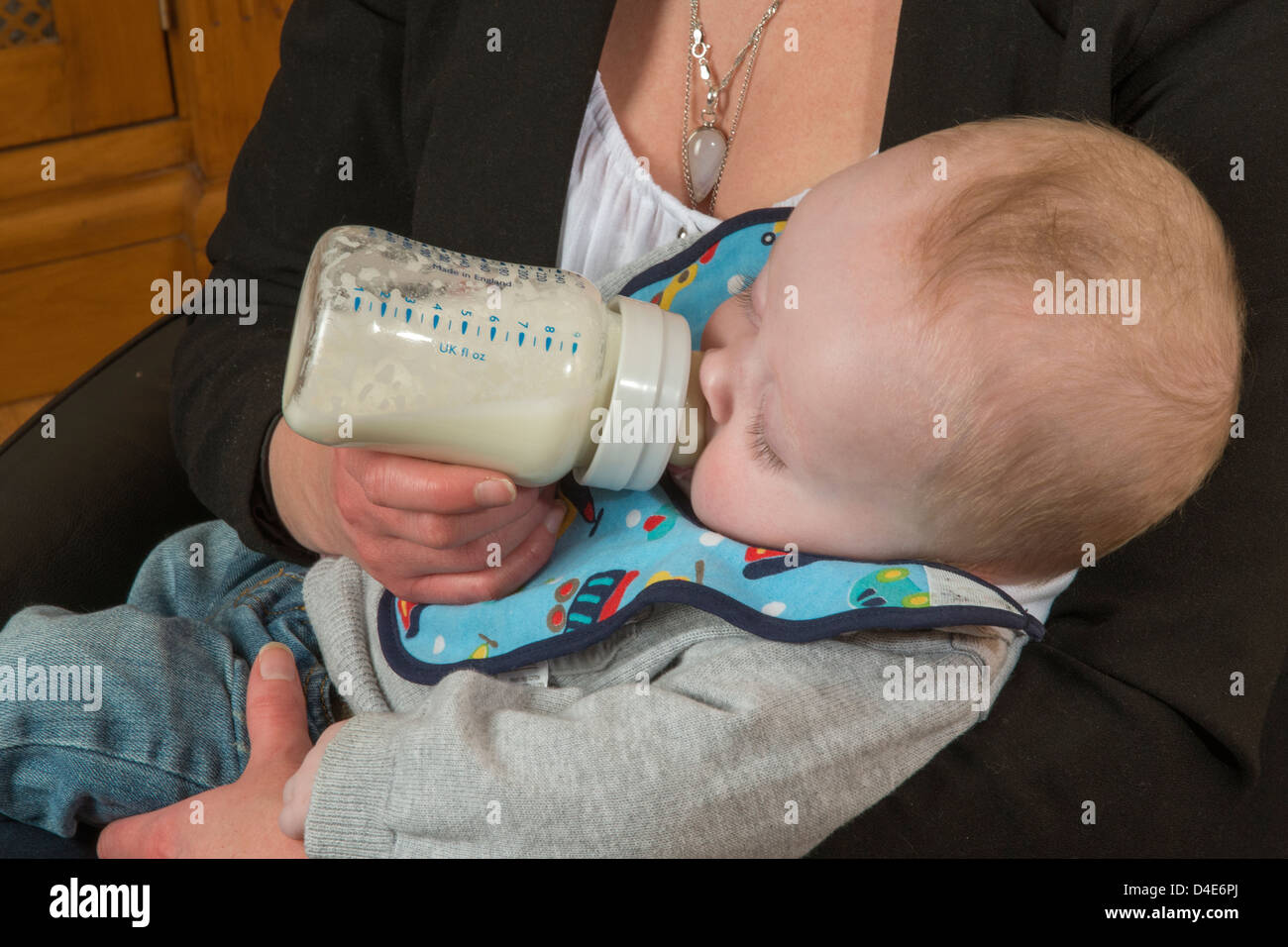 Baby boy being bottle fed by his young mother Six month old child Stock