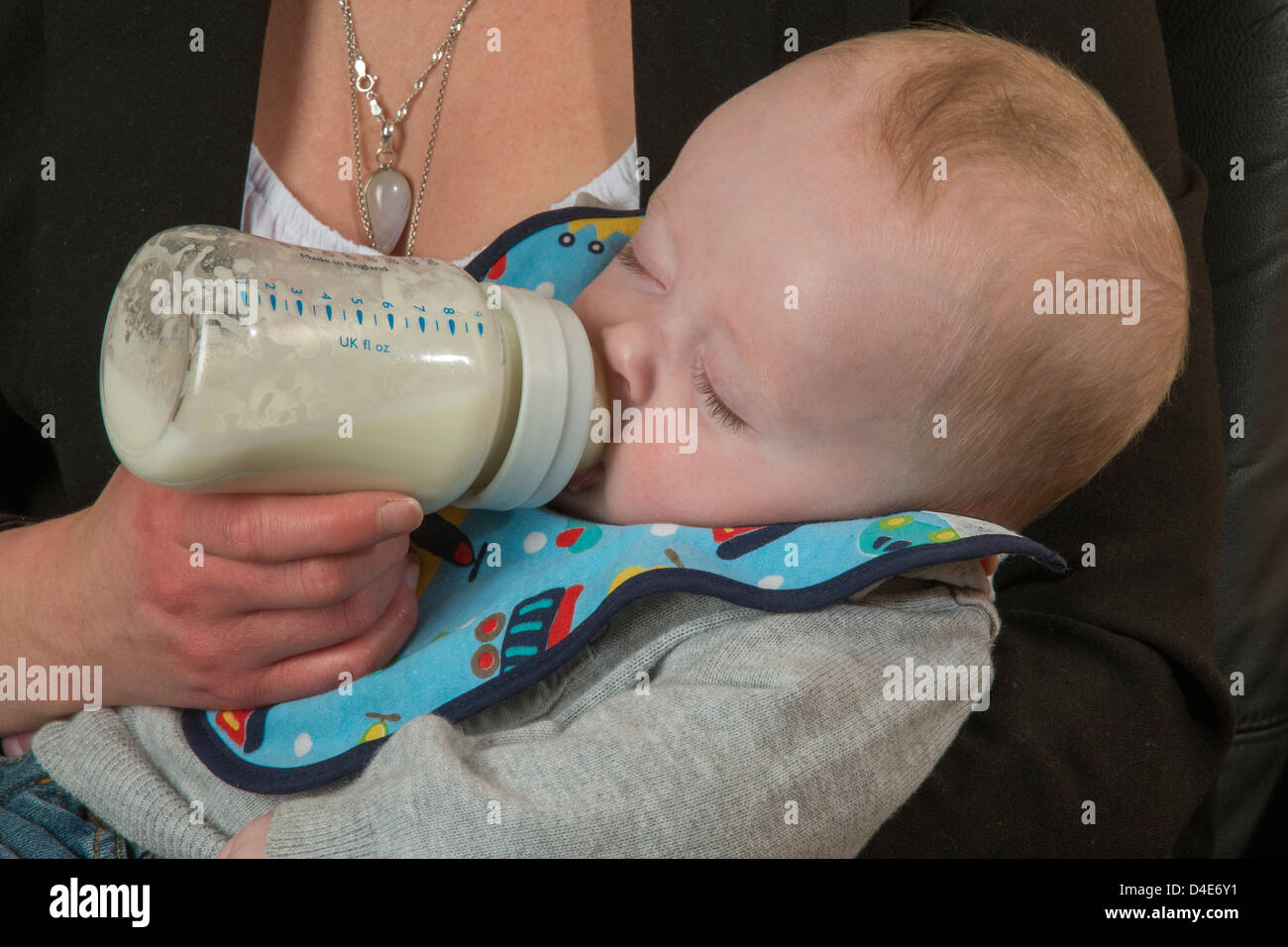 Baby boy being bottle fed by his young mother Six month old child Stock