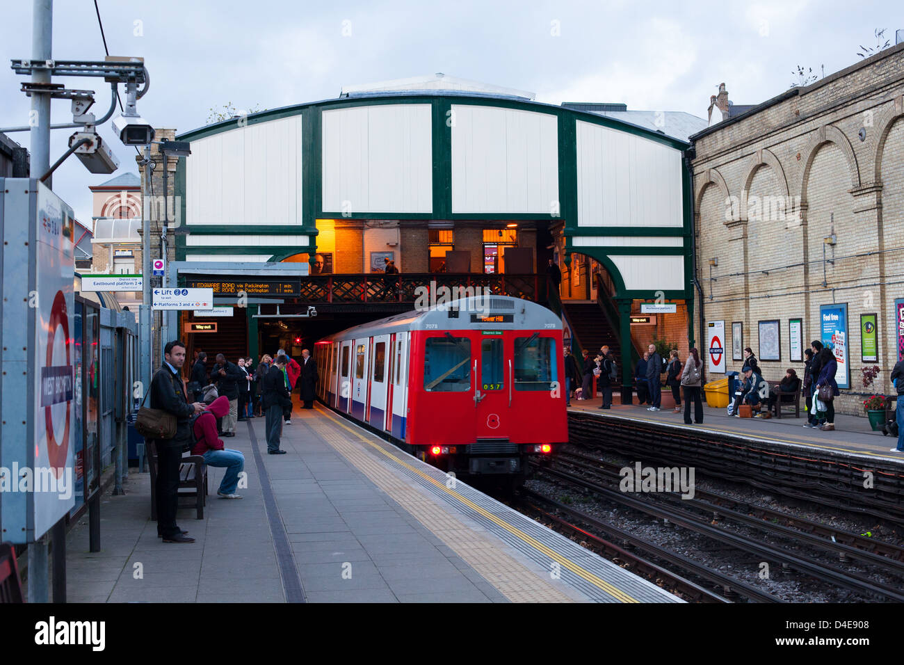 London District line tube underground train is leaving West Brompton station.  People waiting on platform for another train to home Stock Photo - Alamy