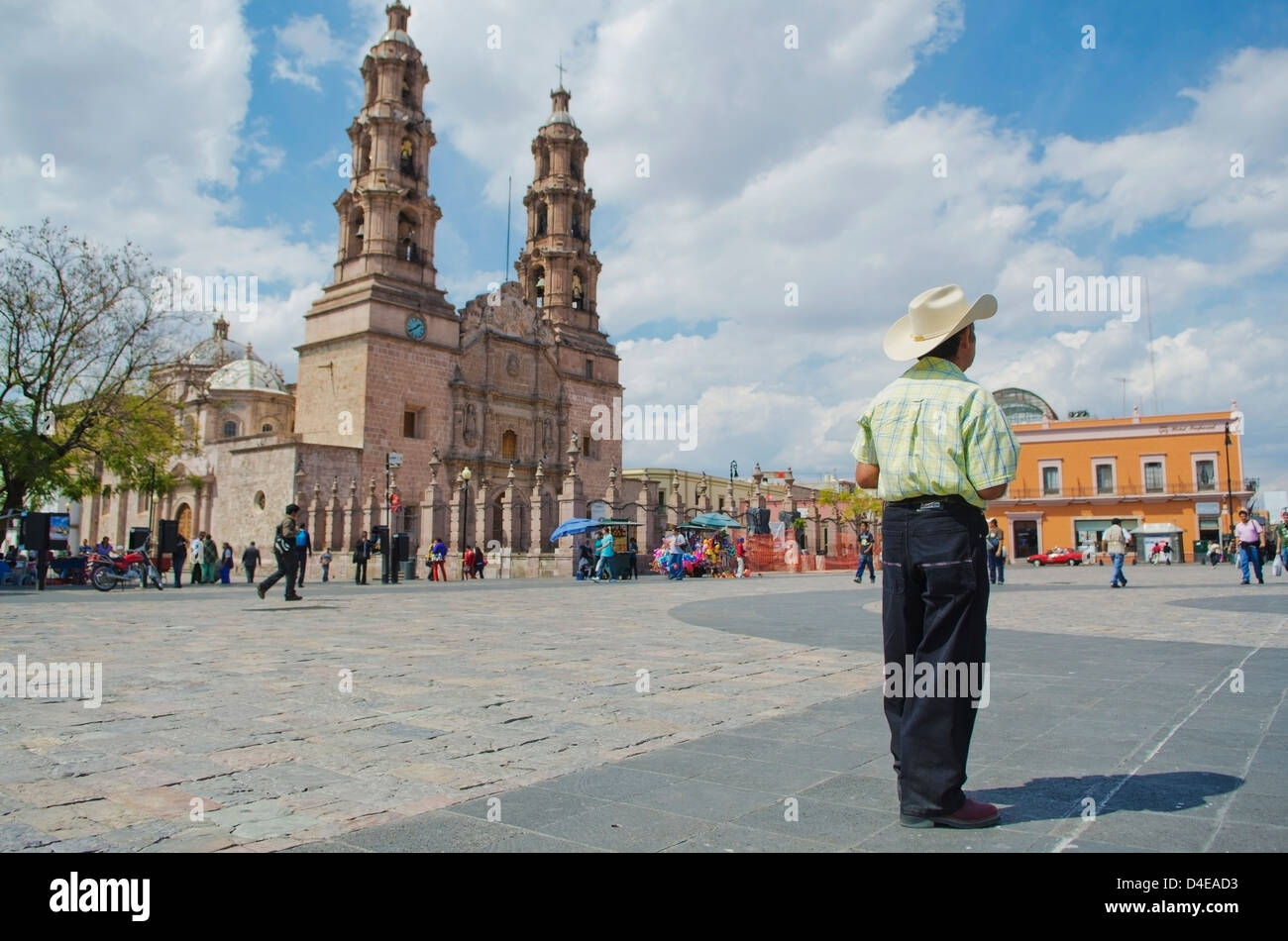 Man wearing cowboy hat standing in large city plaza beside large cathedral; Aguascalientes, Aguascalientes state, Mexico Stock Photo